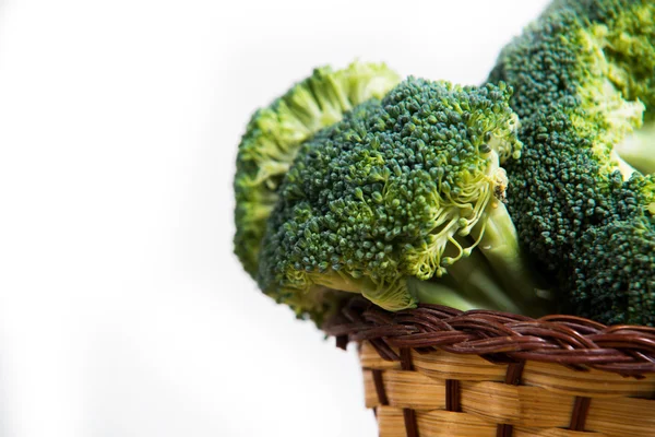 Close up on Fresh broccoli solated in basket on wood and white background — Stock Photo, Image