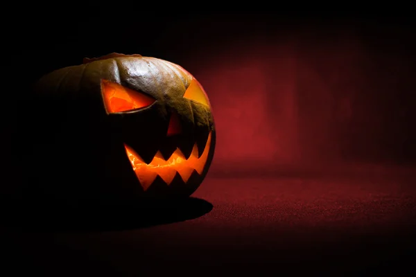 Snidade ansiktet av pumpa glödande på Halloween på röd bakgrund — Stockfoto