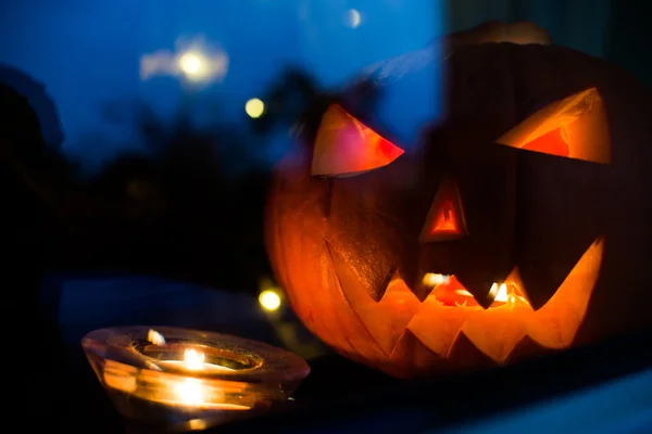 Halloween pupkin symbool achter het home venster met lichte reflectons bij nacht — Stockfoto
