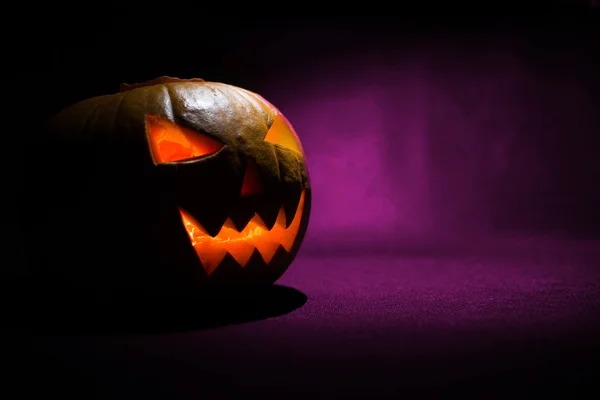 Snidade ansiktet av pumpa glödande på Halloween på lila bakgrund — Stockfoto