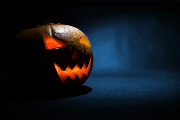 A faragott arca tök izzó a Halloween, a kék háttér — Stock Fotó