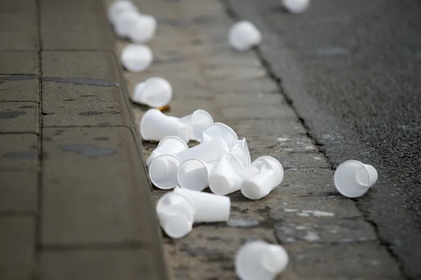 Copas de agua usadas bordean la calle mientras los corredores pasan por una estación de agua en maratón — Foto de Stock