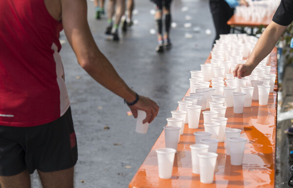 Runner taking cup of water during marathon race, provided by volunteer