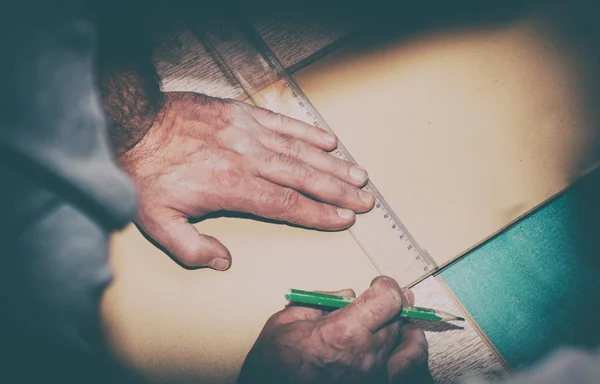 Oldtimer-Foto eines Arbeiters, der mit Lineal eine Linienmarkierung auf eine Holztafel zeichnet — Stockfoto