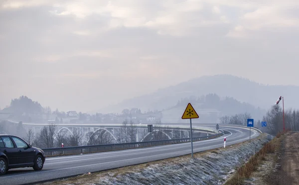 Samochód w zaśnieżonej drodze z mrożonych znak w zimie — Zdjęcie stockowe