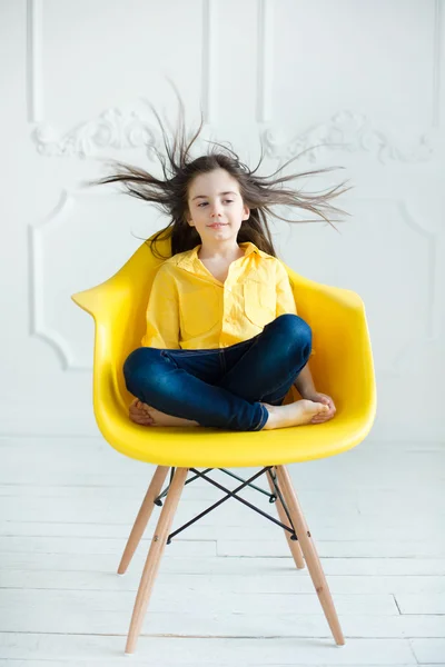 Ragazza seduta su una sedia gialla — Foto Stock