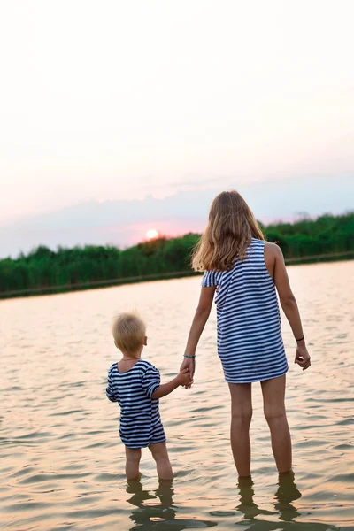日落时两个孩子站在水中 — 图库照片
