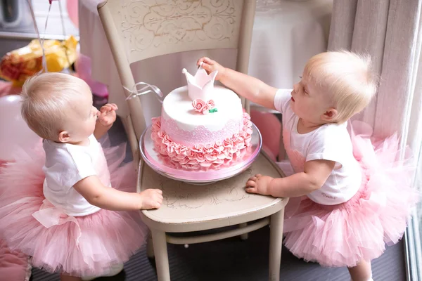 Zwei kleine Mädchen eineiige Zwillingsschwestern. geschmückter Geburtstagskuchen — Stockfoto