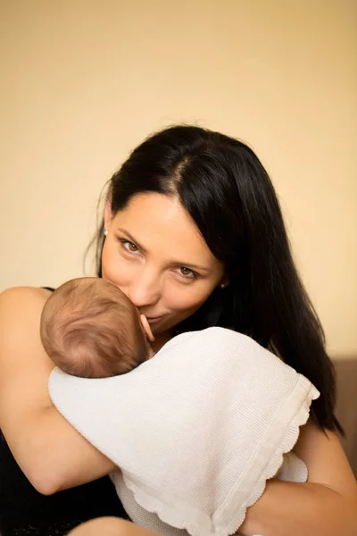 Young mother kissing her newborn child — Stock Photo, Image