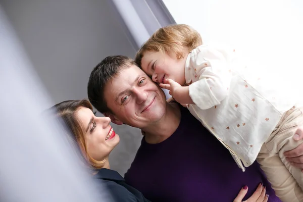 Happy family hugging near window — Stock Photo, Image