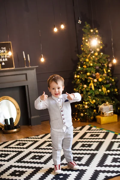 Lyckligt barn boywith julklappar nära en julgran — Stockfoto