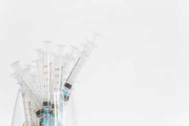 Boş tıbbi şırıngalar konteynırlarda, beyaz arka planda yatıyor.