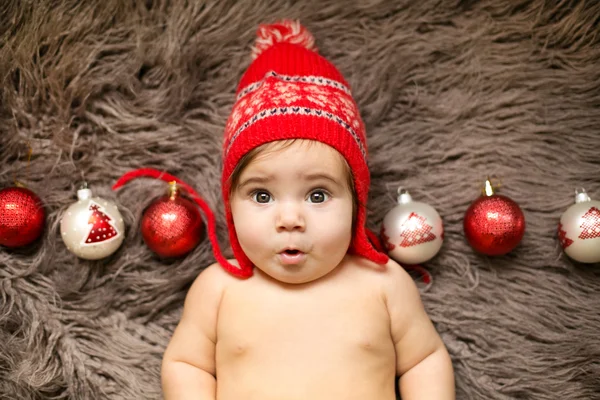 Baby i röd mössa med julgranskulor — Stockfoto