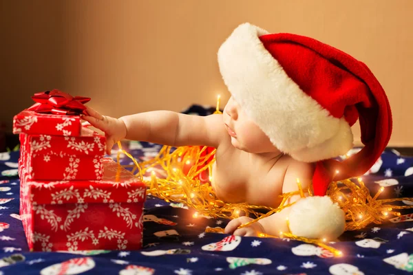 Bébé en chapeau de Père Noël avec cadeaux de Noël — Photo