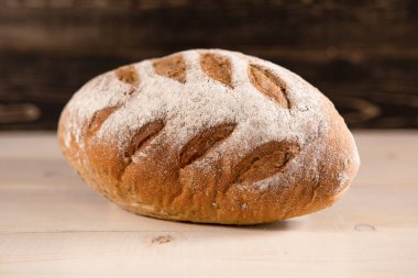 Hafif ahşap arka planda bir somun taze ekmek.