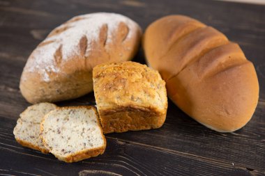 Koyu ahşap bir masada taze ekmek çeşitleri.