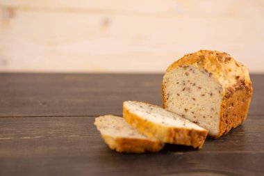 Koyu ahşap mutfak masasında kepekli ekmek ve arpa dilimleri.