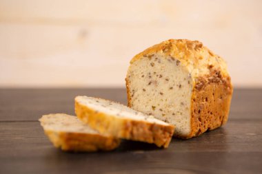 Koyu ahşap mutfak masasında kepekli ekmek ve arpa dilimleri.