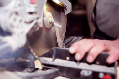 Bir işçi dairesel bir makinede ahşap bir tahtayı işlemeye konsantre oluyor.