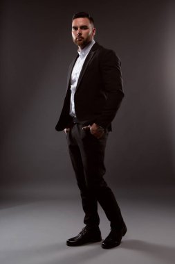 Siyah takım elbiseli ve beyaz gömlekli yakışıklı bir adam. Siyah arka planda duran bir iş adamı. Yakın plan fotoğraf.