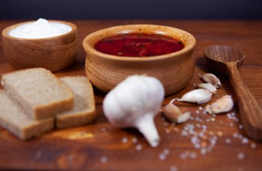 Çavdar ekmeği ve sarımsaklı siyah ahşap zemin üzerine kırmızı borş çorbası. Etli, ekşi kremalı ve dereotlu çorba..