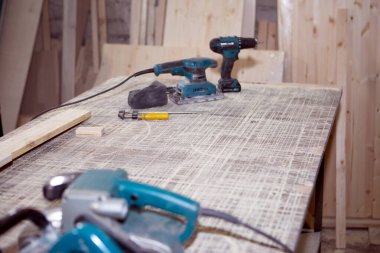 Ahşap işçiliği için bir güç aracı çalışma gününün sonunda masaüstünde tozlu yatar