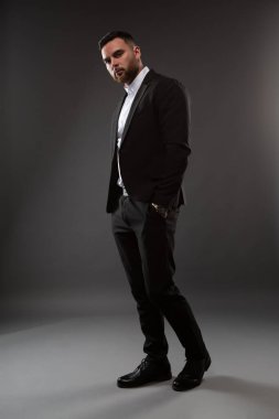 Siyah takım elbiseli ve beyaz gömlekli yakışıklı bir adam. Siyah arka planda duran bir iş adamı. Yakın plan fotoğraf.