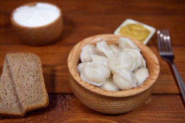 Et, ravioli ile doldurulmuş lezzetli hamur köfteleri ahşap bir masada soslar ve ekmekle birlikte. Doldurulmuş börek. Rus mutfağı..