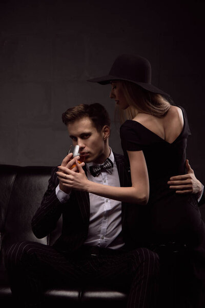 Богатый красивый мужчина пьет виски с блондинкой-любовницей вечером при низком освещении. Фотографии влюблённой пары