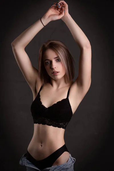 Prachtig sexy meisje in ondergoed poseren in de studio op een zwarte achtergrond. — Stockfoto