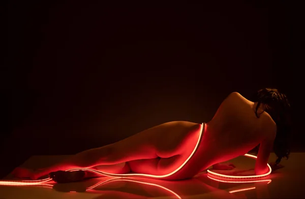 Fashionable artistic photo of an elegant nude model in the light of colored light ribbons Royalty Free Stock Photos