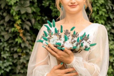 Havadar bir elbise içinde zarif bir buket çiçekle güzel, ince bir gelin. Yeşil elbiseli kız.