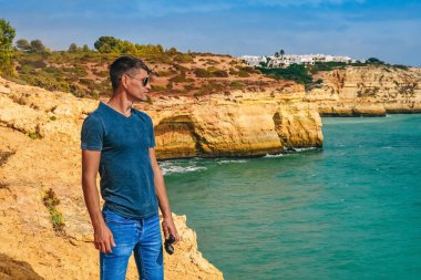 İnce bir adam Portekiz 'de bir kayanın üzerinde duruyor. Adam uzaklığa bakıyor, okyanus hayatı.