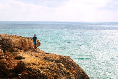 Zayıf bir adam Portekiz 'de bir kayanın üzerinde duruyor. Adam önüne bakıyor, okyanus hayatı.