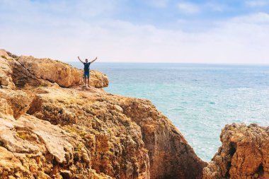 Zayıf bir adam Portekiz 'de bir kayanın üzerinde duruyor. Adam önüne bakıyor, okyanus hayatı.