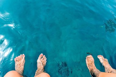 güzel parlak mavi su, su yüzeyinin dokusu mavi renk, kadın ve erkek kıllı bacaklar su üzerinde