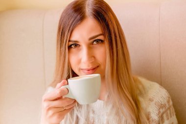 Güzel, seksi sarışın elinde bir fincan kahve tutuyor. Kız nefis bir içkinin, sabah ayininin tadını çıkarıyor.