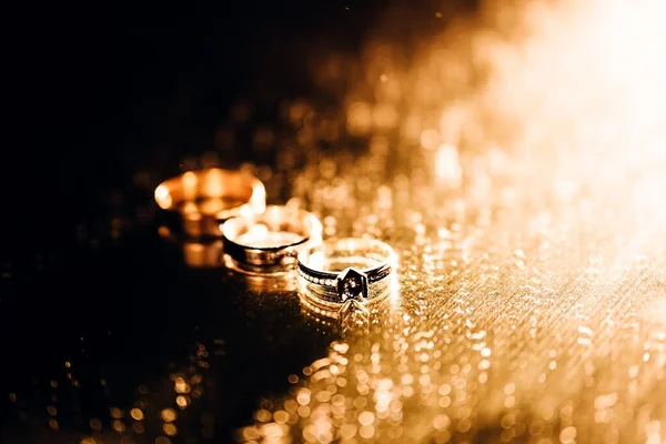三枚金戒指在镜子的背景上相邻而立 结婚戒指的饰物在黑色的背衬下 — 图库照片