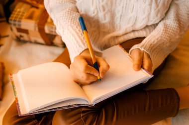 Güzel seksi kız elinde defterle yatakta oturuyor ve hayaller kuruyor. detaylar kapat..