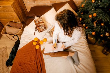 Siyah saçlı beyaz kazaklı güzel kıvırcık kız yatağa oturur ve bir deftere yazar. Mutlu yıllar portresi, bir dilek tutar ve bir mektup yazar. Siyah köpek yakınlarda oynuyor.