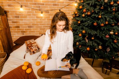 Siyah saçlı beyaz kazaklı güzel kıvırcık kız yatağa oturur ve bir deftere yazar. Mutlu yıllar portresi, bir dilek tutar ve bir mektup yazar. Siyah köpek yakınlarda oynuyor.