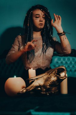 Mavi saçlı kız gece karanlik bir odada, mum yanginda ve inek kafasinda...