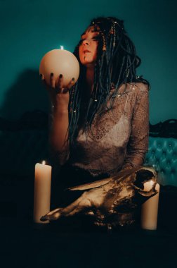 Mavi saçlı kız gece karanlik bir odada, mum yanginda ve inek kafasinda...