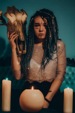 Mavi saçlı kız gece karanlik bir odada, mum yanginda ve inek kafasinda...