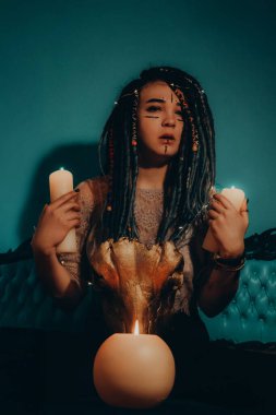 Mavi saçlı kız gece karanlik bir odada, mum yanginda ve inek kafasinda...