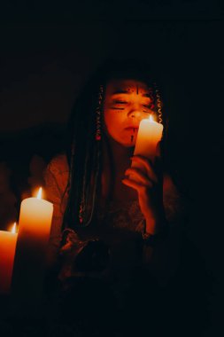 Mavi saçlı kız gece karanlik bir odada, mum yanginda ve inek kafasinda...