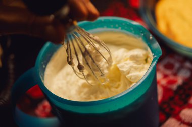 Kadın elleri pasta için krema çırpıyor, tereyağı tabağı pişiriyor.