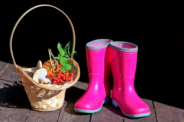 Basket with mushrooms and rubber boots