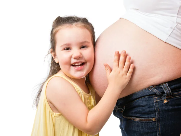 Smiling little girl holding belly of pregnant mother — Stock Photo, Image
