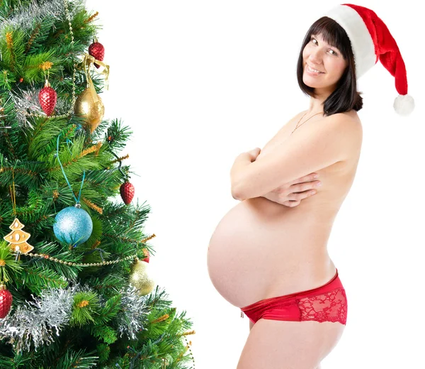 Schwangere junge Frau nahe geschmücktem Weihnachtsbaum — Stockfoto